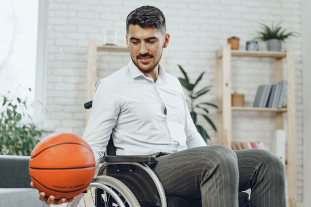 男性轮椅上的残疾青年在室内拿着篮球球恢复受伤