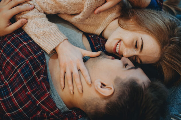 微笑俯瞰图：一对年轻可爱的夫妇 面带微笑地倚在床上 早上在家里接吻浪漫躺着室内