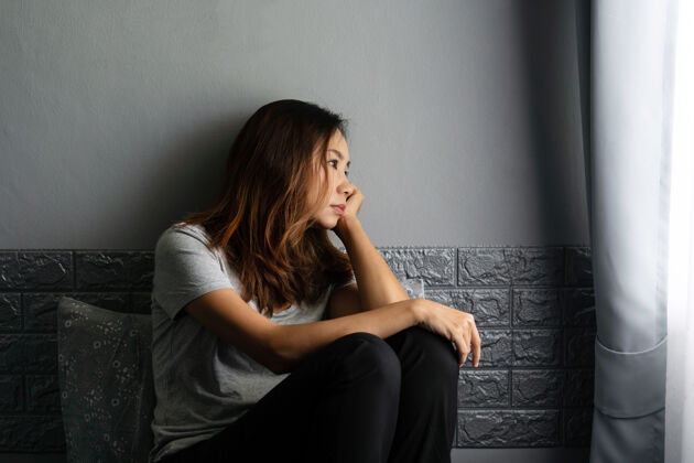 女孩压力重重的亚洲年轻女子患抑郁症 独自坐在家里黑暗的房间里的床上脸人早晨