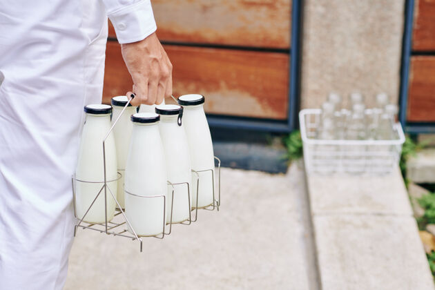 成人送货员端着几瓶鲜奶来到门口的特写镜头步行房子乳制品
