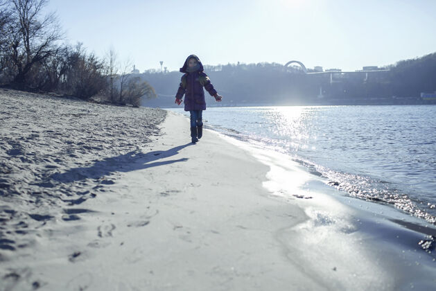散步孩子们沿着河岸散步 享受冬日的阳光思想孤独寒冷
