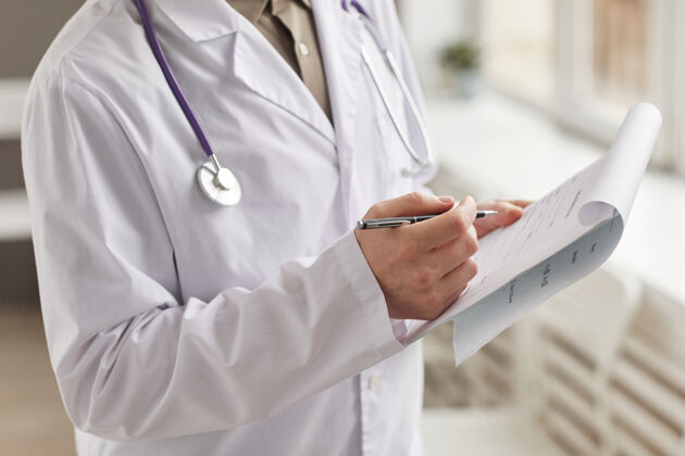 工作白衣医生在医院用钢笔填写医疗卡的特写镜头护理人员文件药品