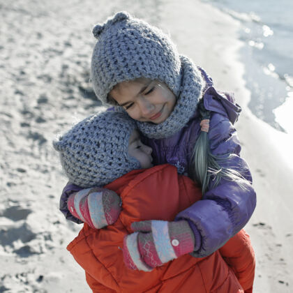 姐姐一家人一起过冬 孩子们冬天在沙滩上散步微笑友谊编织帽子