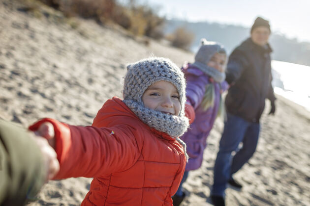 朋友一家人一起过冬 孩子们冬天在沙滩上散步哥哥寒冷女儿
