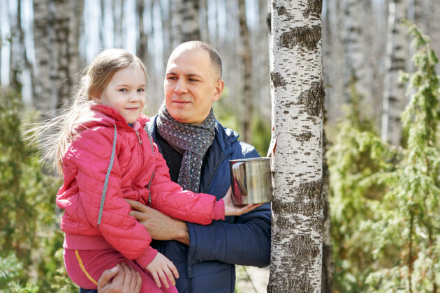 桦树父女俩在树林里拿着一个收割用的杯子家庭人父母