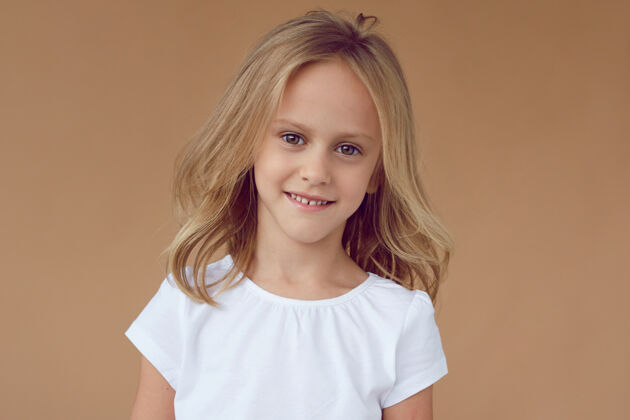 工作室前面的肖像是一个漂亮的小女孩 卷曲的金发 穿着白色的衣服小童年时尚