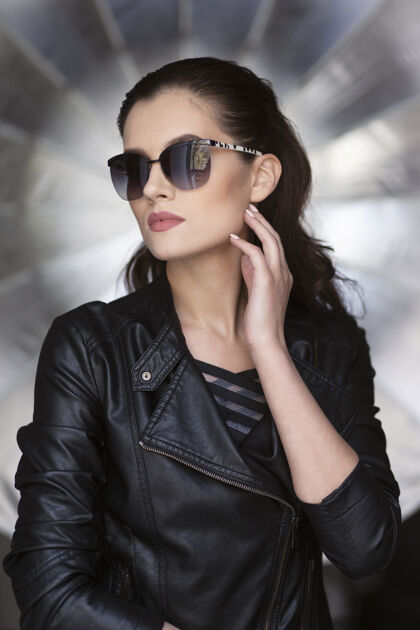 工作室性感时尚的黑发女模特的正面肖像 穿着黑色皮夹克和时尚的太阳镜深色夹克皮革