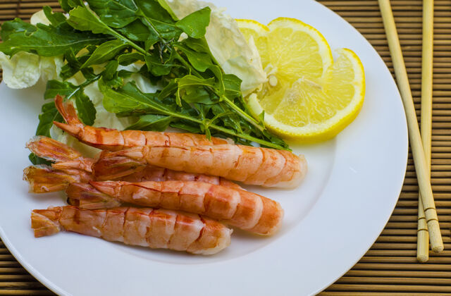 美味放在盘子里的虾加柠檬和沙拉生鱼片海鲜午餐