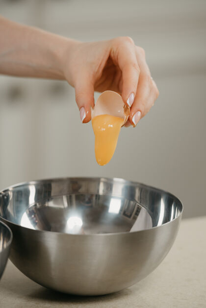 准备一个年轻女子的手倒在厨房不锈钢碗蛋黄的亲密照片烹饪女手工