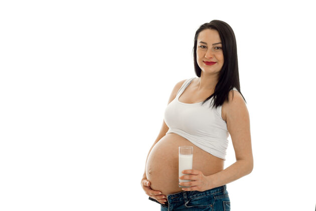 人年轻漂亮的怀孕的黑发女人在白墙上摆着孤立的姿势腹部爱生活