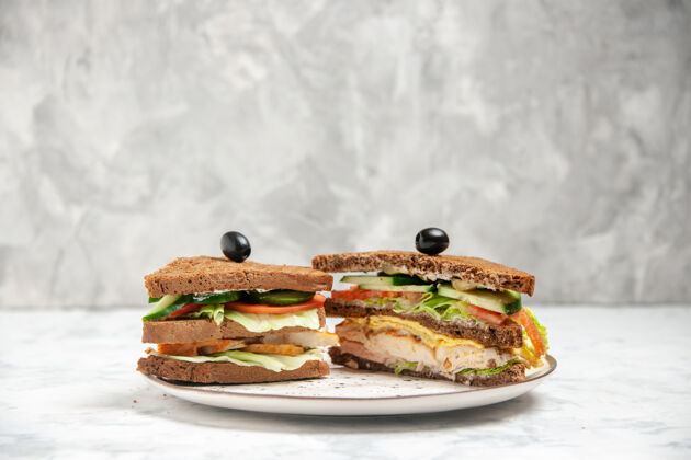 午餐美味三明治的正面图 黑色面包上涂有橄榄油 盘子上有白色污渍肉螃蟹美味三明治