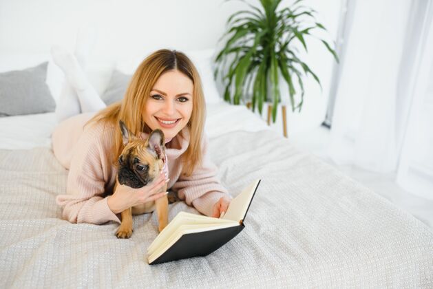 孕妇年轻女人带着狗和书在家里放松 看书成人父母女人