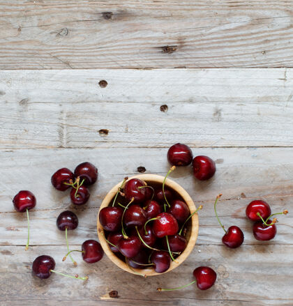 有机红色樱桃在一个旧的木制背景碗生的甜点浆果