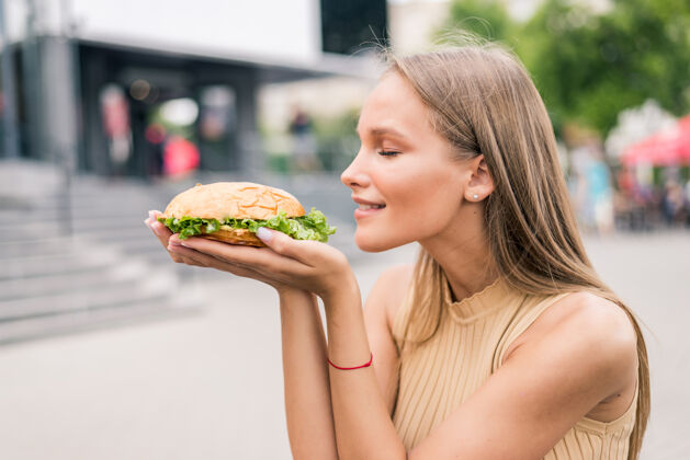 不健康美女在街上吃美味漢堡包的畫像面包奶酪發髻
