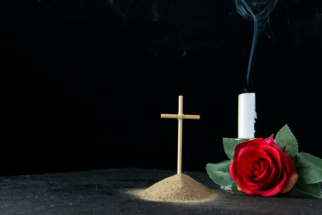 墓地黑暗中有鲜花和蜡烛的小坟墓的正视图鲜花玻璃蜡烛