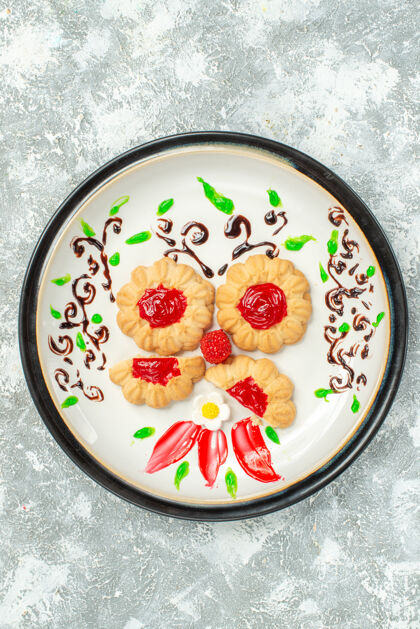 托盘顶视图美味饼干与红色果冻内板上的白色背景蛋糕饼干甜茶茶碗陶瓷器皿
