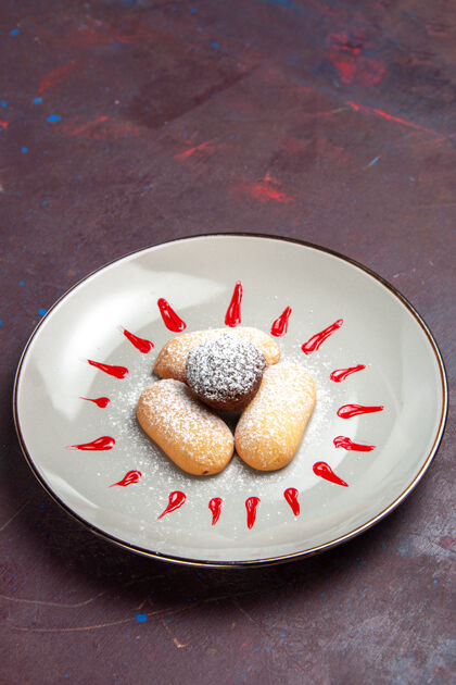 食物前视图美味饼干与糖粉和红色糖衣内板上的黑暗空间盘子霜水果