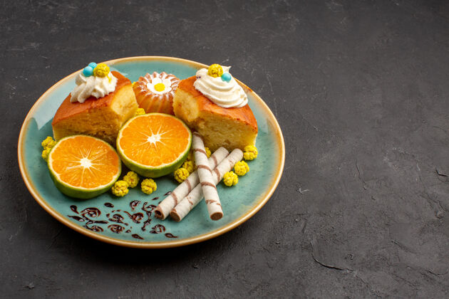 美味的蛋糕片前视图美味的蛋糕片与烟斗饼干和切片橘子在黑暗的空间水果可食用的水果柑橘