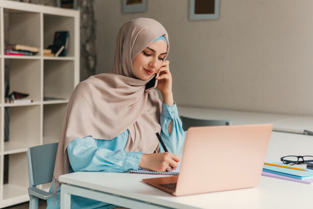 女性年轻漂亮的现代妇女戴着头巾在办公室的笔记本电脑上工作 教育在线移动围巾文化