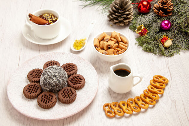 早餐正面是美味的巧克力饼干 白色桌面上有小可可蛋糕和茶 茶蛋糕甜饼饼干饼干食物前面餐