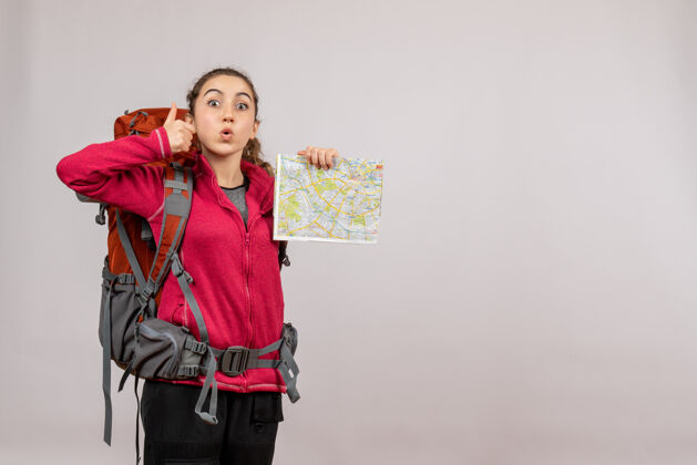 拇指正面图拿着大背包的年轻旅行者竖起大拇指示意图持有年轻的旅行者度假