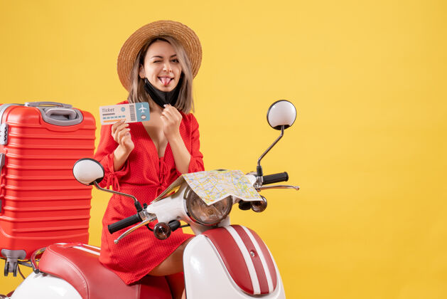 摩托车正面图：坐在轻便摩托车上的年轻女士 红色手提箱伸出舌头 手里拿着车票抱着肖像成人