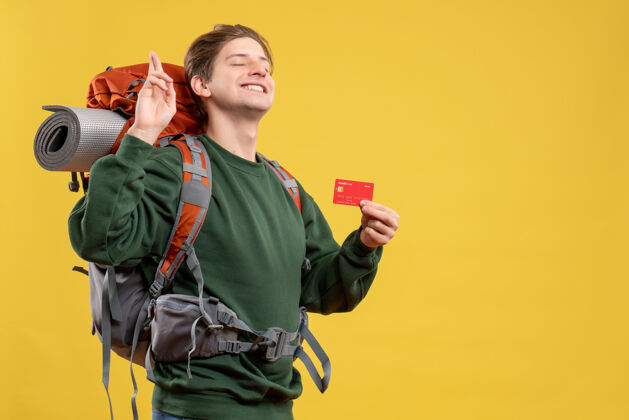 人正面图年轻男子手持红色银行卡准备远足飞行旅游信用卡