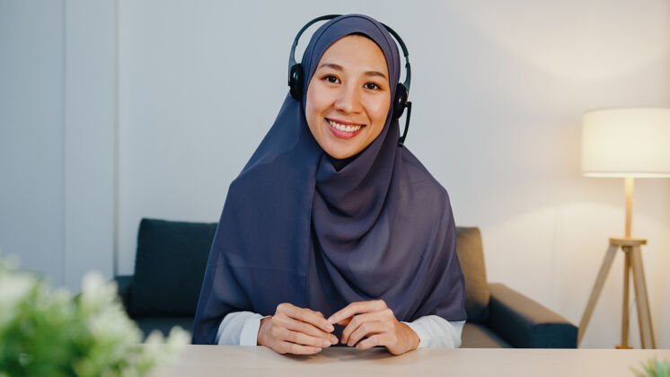 女士戴着耳机 用笔记本电脑 晚上在家办公的时候 在电话会议上和同事谈论销售报告头巾人员工作