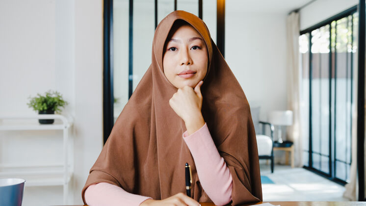聊天亚洲女士戴着头巾用笔记本电脑在客厅远程工作时 在视频电话会议上和同事谈论计划技术阿拉伯语会议