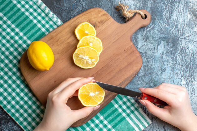 饮食上图是一只手在深色背景的木制砧板上切碎新鲜柠檬深色柚子切