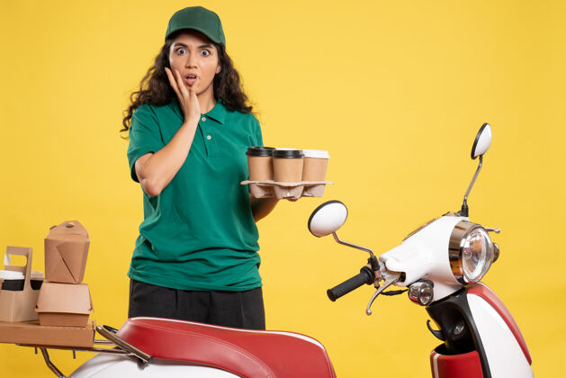 制服正面图身着绿色制服的女快递员 咖啡色背景为黄色服务人员工作递送工作食物的女服务员工作咖啡服务