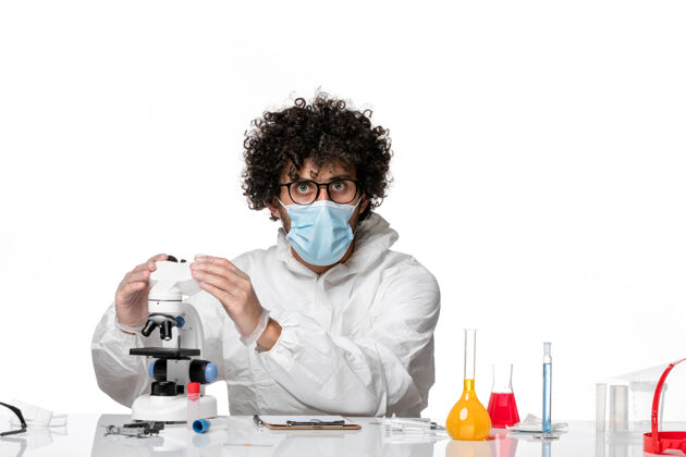 化学药品男医生穿着防护服 戴着口罩 用显微镜在白色上工作外套防护罩男医生
