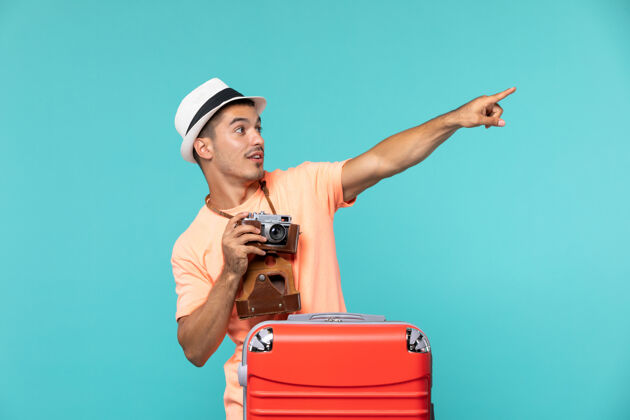 相机带着他的大红色手提箱和蓝色相机的度假男人肖像人物旅行