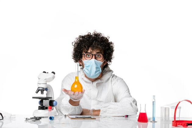 药品正面图：男医生穿着防护服 戴着口罩 手里拿着白色的黄色溶液大流行实验室专业