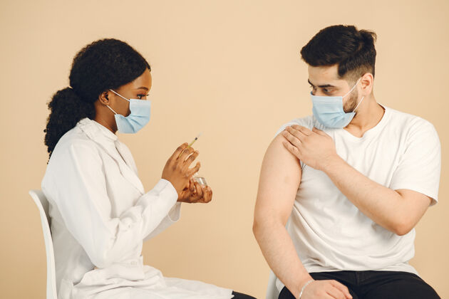 集体一位非洲裔美国医生给一名男子注射疫苗两人都戴着口罩 隔离接种了covid-19疫苗给药男性安全