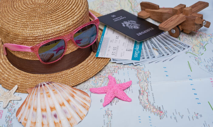 飞机平放旅行配件与棕榈叶 相机 帽子 护照 钱 机票 飞机 地图 太阳镜顶视图 旅游或度假的概念笔记本物体享受