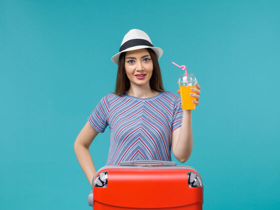 人前景度假中的女人拿着她的红袋子拿着她的果汁在蓝色书桌上旅行夏天海上旅行度假举行航程旅程