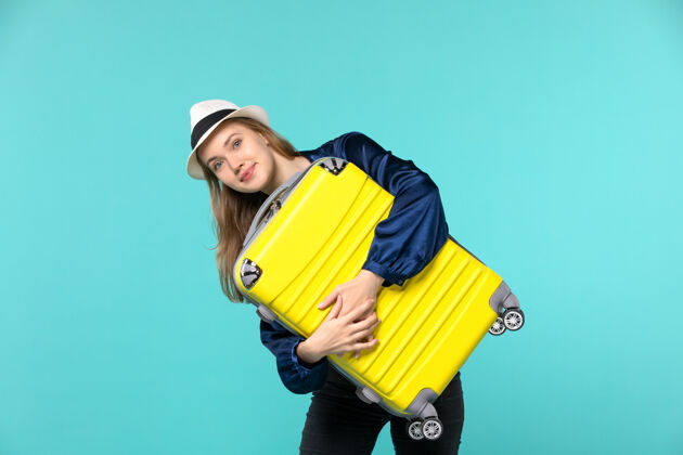 微笑前景：年轻女子在蓝色背景的旅行机上拿着大包去度假救援设备救生圈抱