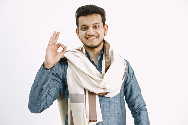 标志年轻的印度男子穿着传统服装 展示ok标志白色墙壁印度人拇指积极