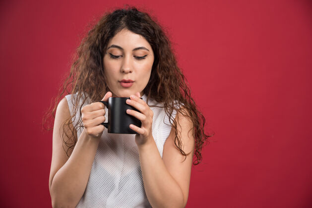 茶一个拿着热黑杯子的女人咖啡杯子红的