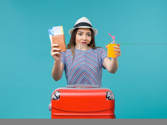 票前景：度假的女人拿着新鲜的果汁和蓝色书桌上的机票旅行 夏天旅行 海上度假果汁航行小