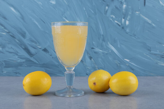 榨汁机新鲜的柠檬和一杯柠檬汁在灰色的表面饮食鸡尾酒健康