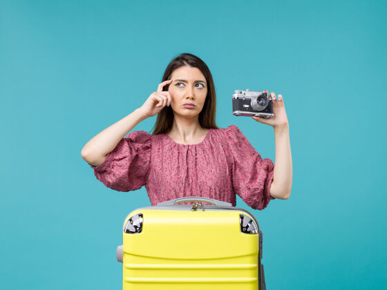 成人前景度假中的年轻女子拿着相机在蓝色书桌上旅行海上旅行女子出国度假抱着肖像年轻的女人