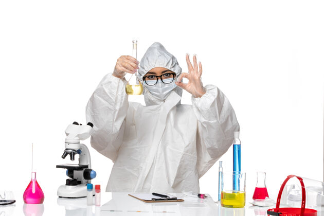 实验室正面图身穿特殊防护服的年轻女化学家拿着装有白色背景实验室病毒化学病毒溶液的烧瓶人员套装病毒