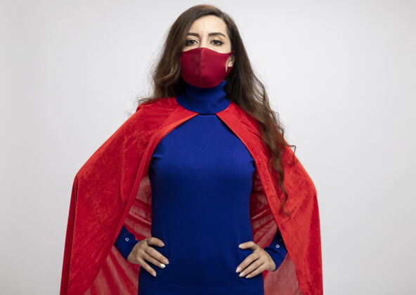超级英雄自信的高加索超级英雄女孩 穿着红色斗篷 戴着红色防护面具腰斗篷手