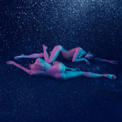 表演两个年轻的女芭蕾舞演员在水滴下年轻平衡舞蹈