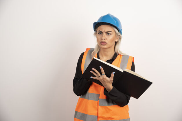 工程师不高兴的工人与笔记本站在白色的背景高品质的照片女头盔女孩