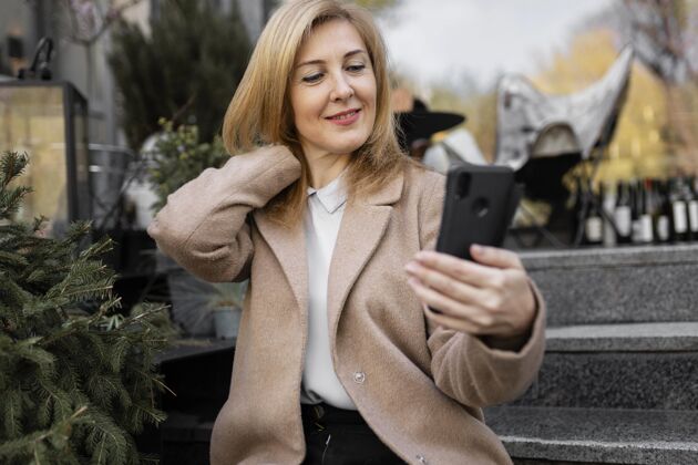人快乐的中年妇女正在检查她的手机城镇成人城市
