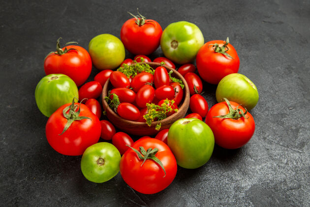 磨碎底部视图樱桃红色和绿色的西红柿围绕一个碗与樱桃西红柿在黑暗的背景蔬菜新鲜樱桃