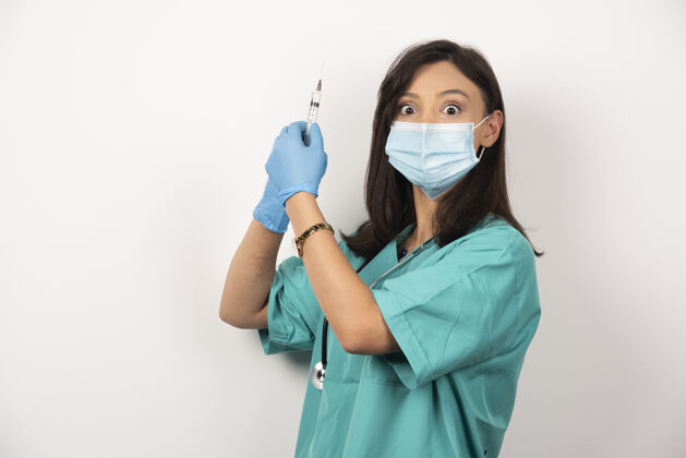 女性戴着医用面罩和手套的女医生拿着白色背景的注射器高质量的照片手套职业药品